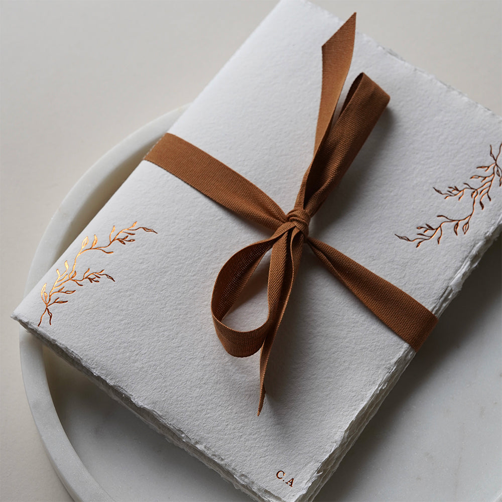 White notebook with hazelnut ribbon and leaf designs on a light background