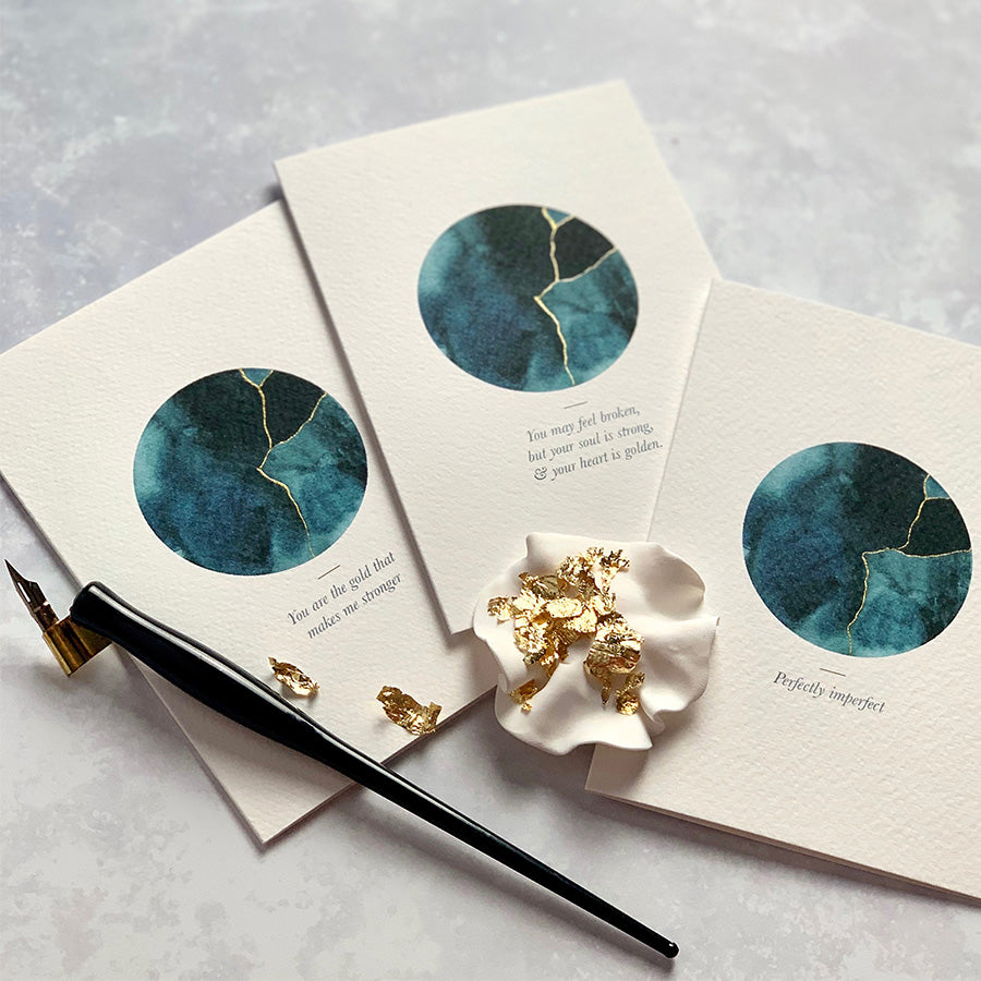 
                      
                        This A6 watercolour Kintsugi greeting card is printed at our studio & features an inky blue watercolour circle with hand-finished gold lines added.
                      
                    